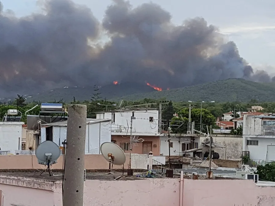 Φλόγες και καπνός σε λόφο πάνω από μια πόλη