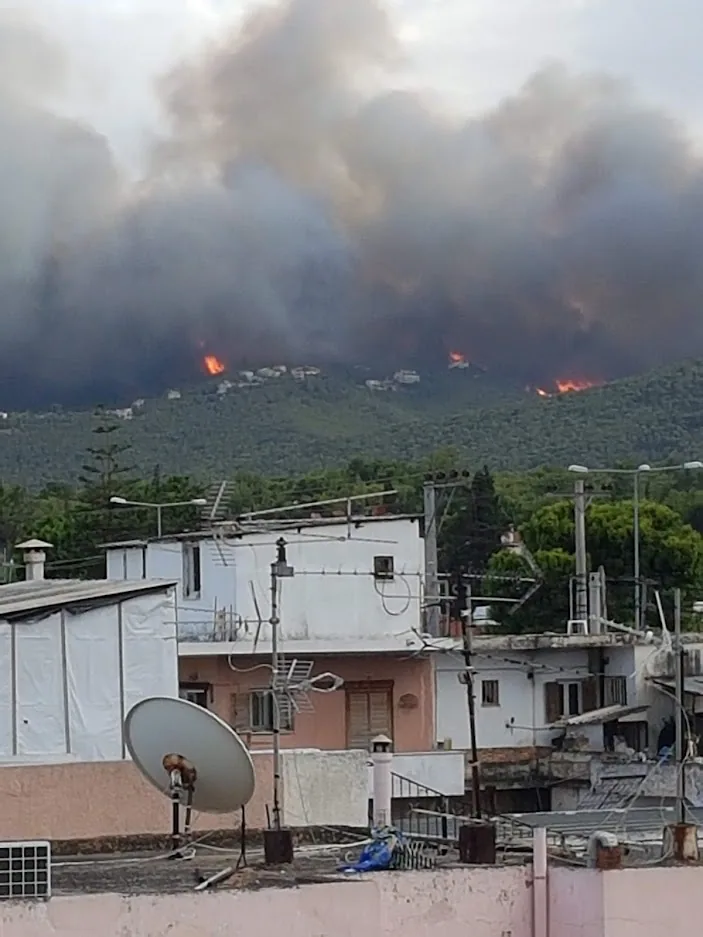 Καπνός από πυρκαγιά υψώνεται πάνω από λόφους πίσω από σπίτια