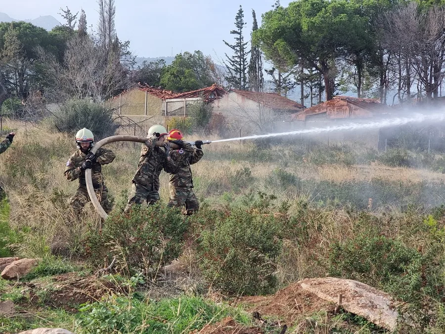 Ομάδα πυροσβεστών κρατά μάνικα στη γραμμή της φωτιάς